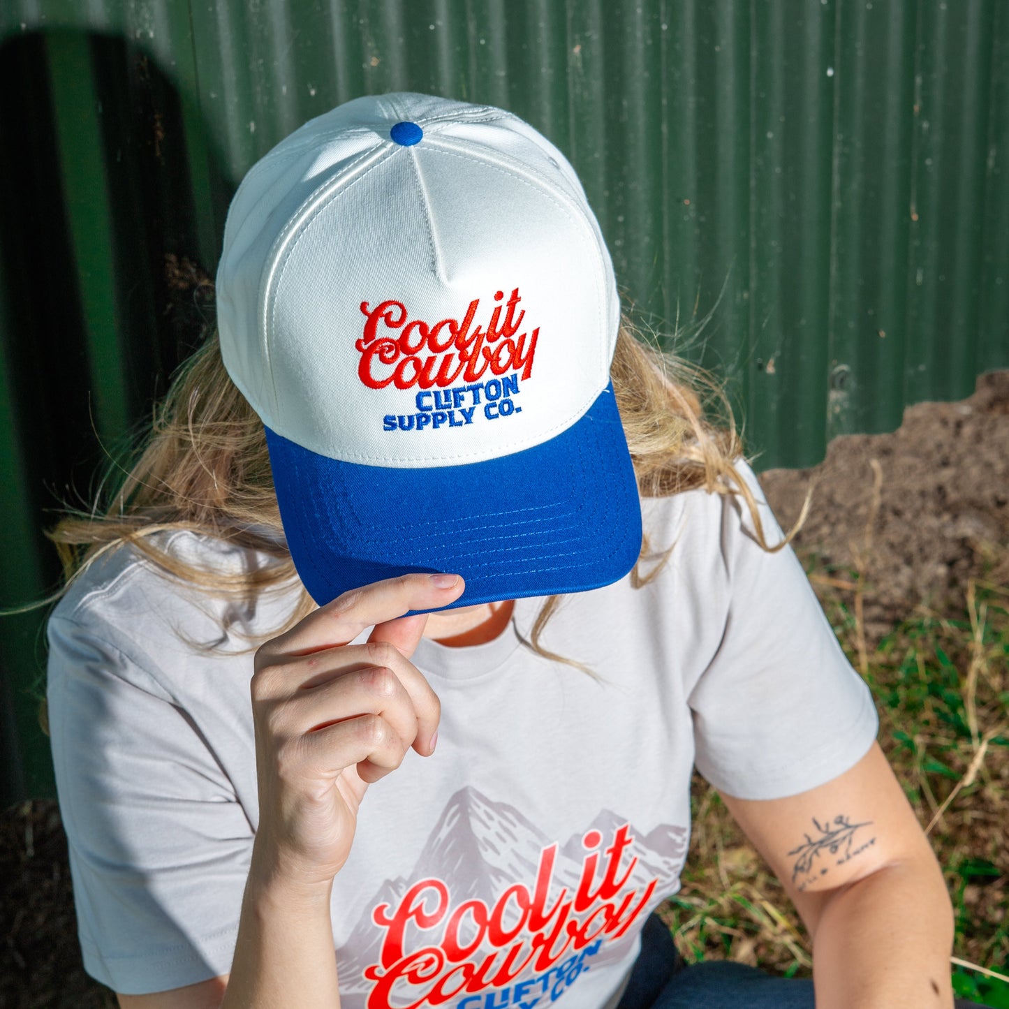 Person wearing a white t-shirt and blue cap with 'Cool it Country' branding.